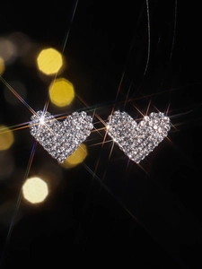 Macro shot of sparkling heart stud earrings with pavé crystals on a bokeh background