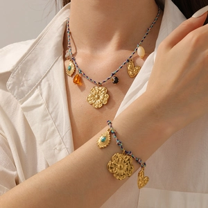 Detail of woven necklace and bracelet set with golden flowers and turquoise pendants