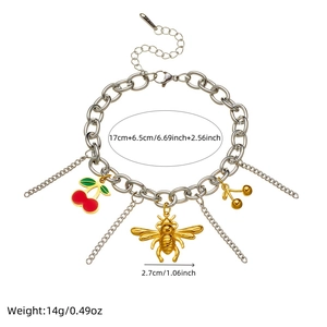Gold bee and red cherry charm bracelet with stainless steel tassels on white backdrop