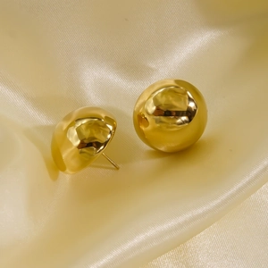 Polished 14K gold plated stainless steel stud earrings on luxury beige silk background