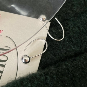 Macro shot of silver bead drop earrings on green knit and white card