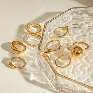 Group of 18k gold plated stainless steel rings with rhinestones on a glass tray