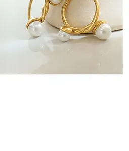 Macro shot of gold twisted metal hoop earrings with a single white pearl detail
