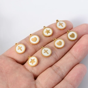 Gold stainless steel shell pendants with cross, heart and star held in palm