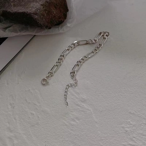Close-up of silver Figaro titanium steel bracelet with adjustable clasp on stone