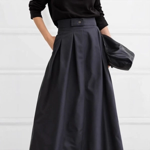 Close-up of high-waist pleated black maxi skirt with wide waistband and buttons