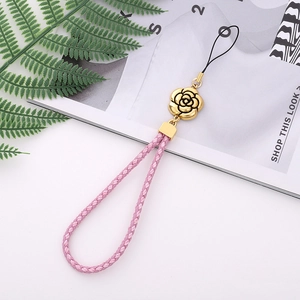 Pink leather braided phone strap with gold plum flower pendant and magazine background