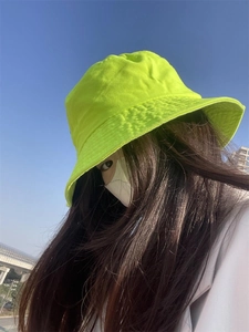 Fluorescent green bucket hat featuring premium cotton stitching details against a clear blue sky
