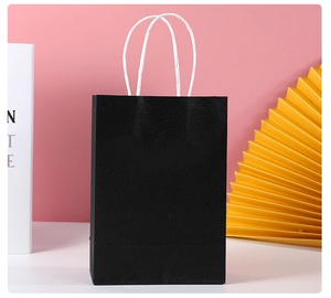Detail of a premium black textured gift bag with white rope handles on a modern background