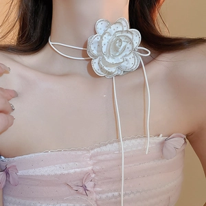Detail of white fabric flower choker with rhinestone edges worn on neck