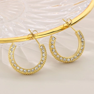 Detailed close-up of C-shaped gold stainless steel earrings with sparkling zircon inlay