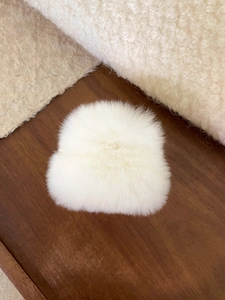 Gros plan sur la texture de la pince à cheveux en peluche blanche sur bois