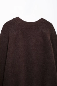 Nahaufnahme des tiefbraunen Strickpullovers mit flauschiger Textur und überschnittenen Schultern