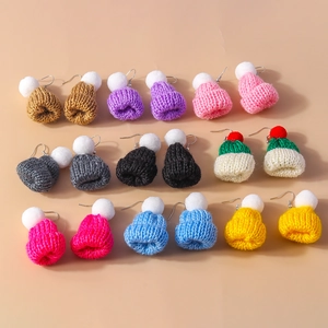 Detail showing various candy-colored knitted hat earrings with soft textures and pom-poms