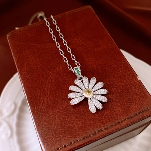 Detail of flower pendant necklace featuring yellow crystal and zircon pavé petals