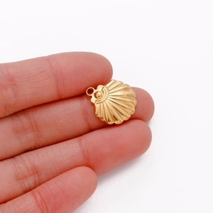 Close-up of a small gold shell pendant held by fingers to show size for DIY jewelry
