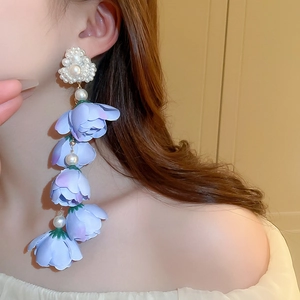 Dettaglio degli orecchini a fiore in tessuto viola con perle sintetiche e nappe