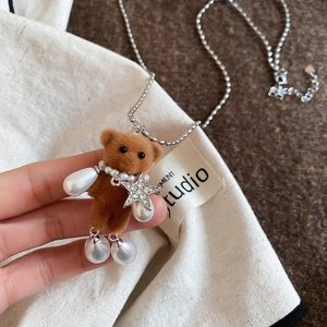 Close-up of brown flocked bear pendant with imitation pearls and star on a steel bead chain