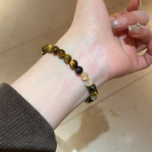 Détail d'un bracelet en perles d'oeil de tigre naturel et perles dorées au poignet