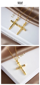 Close-up of gold cross pendant necklace with colorful gemstones and nail design