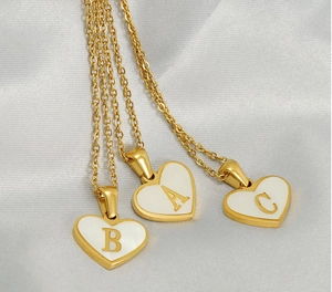 Detail of heart shell alphabet pendant necklaces A B C in gold stainless steel