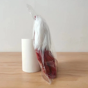 Detail view of the red knitted Christmas stocking with white plush trim in transparent bag