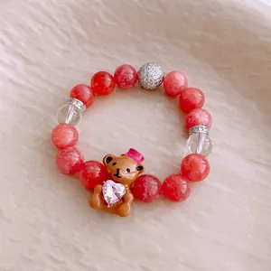 Bracelet en perles roses avec pendentif ourson brun tenant un cristal en cœur rose