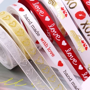 Rolls of Valentine ribbon with gold hearts, red lips, and handmade with love text print