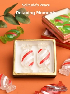 Macro shot of red and green striped resin candy charms in a decorative white gold tray