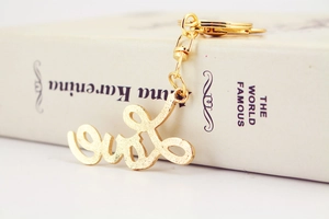 Macro shot of gold LOVE script keychain with rhinestones on a white book spine