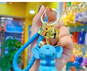 Close-up of cute blue elephant keychain with gold crown pearl and woven leather strap