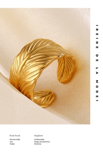 Detail of gold-plated feather ring with intricate textures on soft satin background