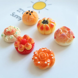 Macro shot of 6 assorted resin miniature bread charms on a white ceramic plate
