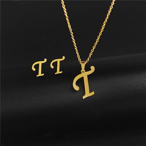 Macro detail of gold stainless steel 'T' initial necklace and matching stud earrings set