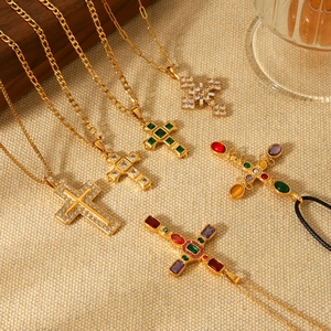 Detailed flat lay of golden cross necklaces with colorful gemstones on beige fabric