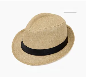 Detail shot of a cream woven straw fedora hat featuring a classic black ribbon band and texture