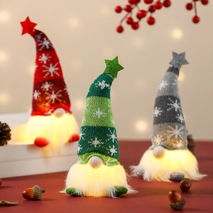 Close-up of three glowing Christmas gnomes with knit star hats in red green and gray