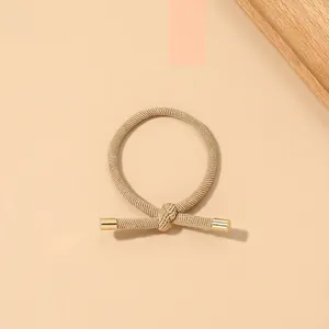 Macro detail of khaki braided hair tie showing ribbed texture and gold metal caps
