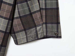 Detailed macro view of grey plaid coat cuffs featuring premium silver metal snap buttons