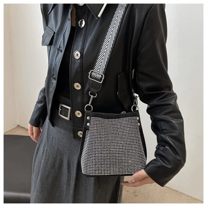 Sac seau tendance à strass avec large bandoulière rayée porté par un mannequin en cuir
