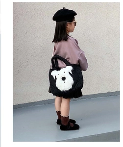 Detailed view of kids black quilted crossbody bag with cute white plush dog motif