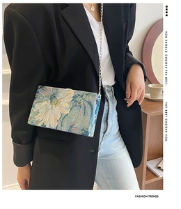 Detail showing jacquard floral fabric texture and slim metal chain on the box clutch bag