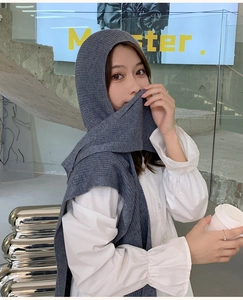 Detail of grey knitted hooded scarf shawl on model in modern industrial interior
