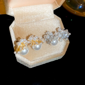 Macro detail of firework pearl earrings with zircons in a beige velvet jewelry box