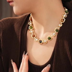 Gros plan d'un collier de perles vintage avec pierres vertes porté par un mannequin