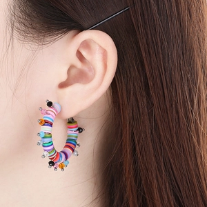 Détail de boucles d'oreilles créoles en perles de résine colorées sur un mannequin