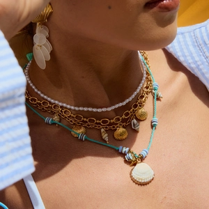 Detail of layered gold shell necklaces and pearl accessories with turquoise cord for women