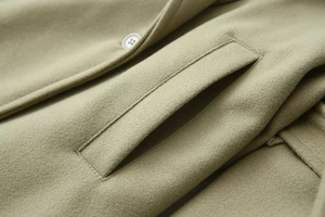 Macro view of olive green woolen coat featuring high-quality pocket and button details