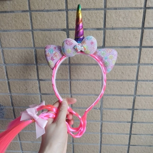 Detail of unicorn headband with rainbow horn, pink sequins, and long synthetic hair braids