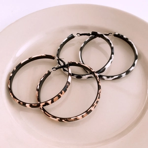 Close-up of leopard and zebra print hoop earrings on a beige ceramic tray